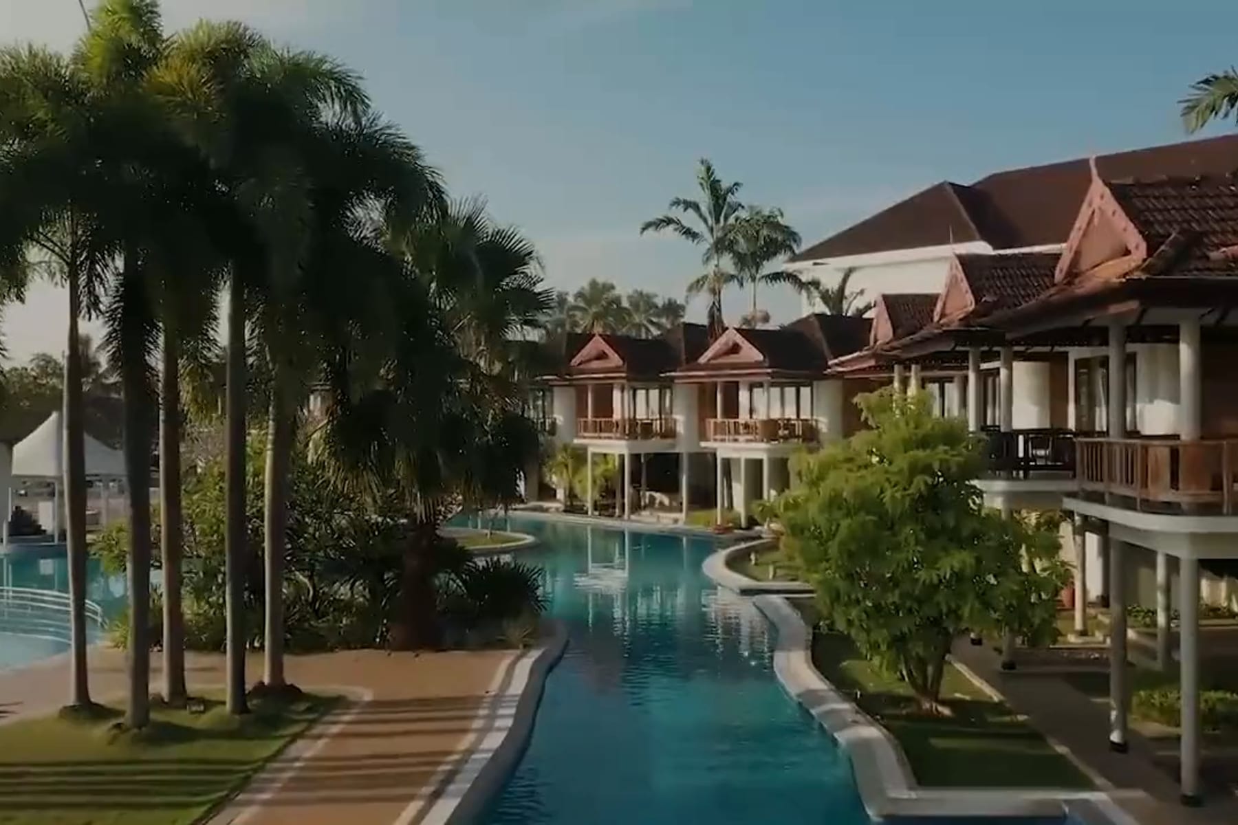 Ramada Resort Kochi from the air: clay-tiled villas along the backwater, the pool, and palms